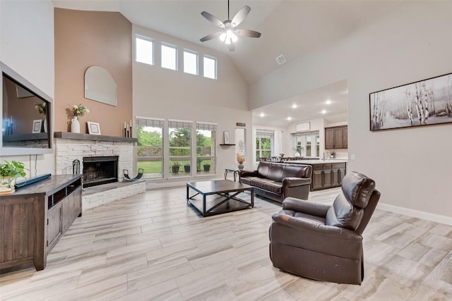 living room featuring ceiling fan, high vaulted ceiling, a fireplace, and baseboards