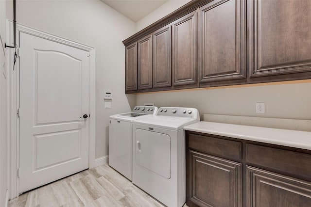 washroom with cabinet space, washing machine and dryer, and baseboards
