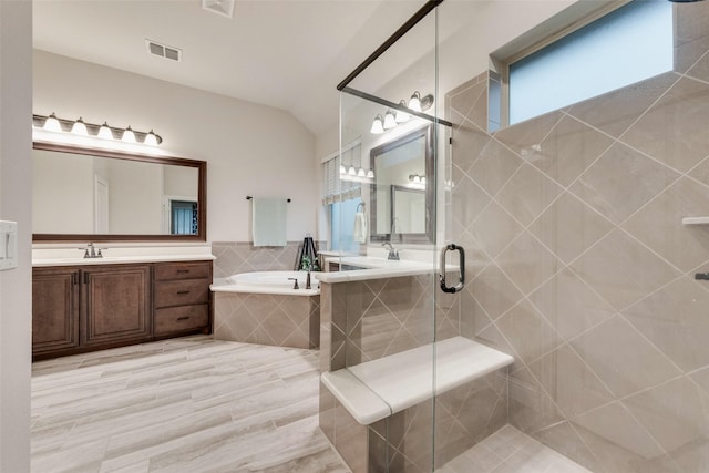 bathroom featuring a garden tub, a stall shower, vanity, and lofted ceiling