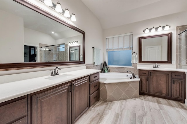 full bath featuring lofted ceiling, a shower stall, a bath, and two vanities