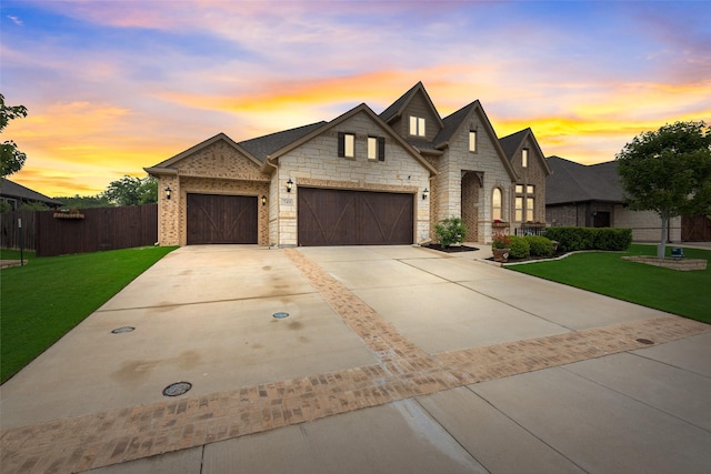 french country style house featuring an attached garage, driveway, and stone siding