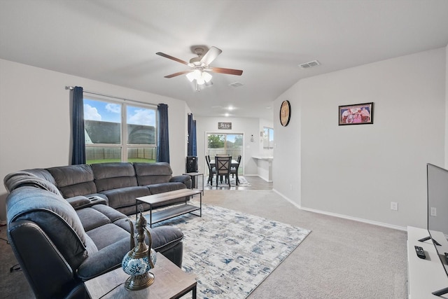 living area featuring baseboards, ceiling fan, light colored carpet, and visible vents