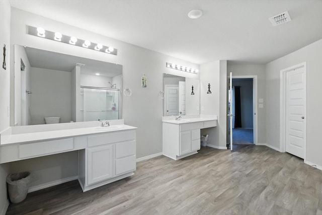 full bathroom with a sink, baseboards, wood finished floors, visible vents, and a stall shower