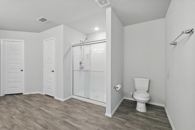 bathroom featuring baseboards, visible vents, a shower stall, and wood finished floors