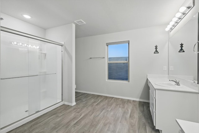 bathroom featuring vanity, baseboards, a shower stall, wood finished floors, and visible vents