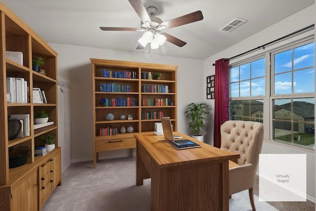 home office with a ceiling fan, baseboards, visible vents, and light carpet