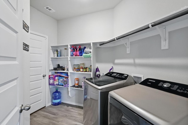 washroom with laundry area, visible vents, light wood-style floors, baseboards, and washer and clothes dryer