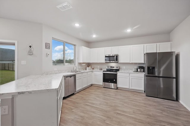 kitchen featuring light wood-style floors, a sink, white cabinets, and stainless steel appliances