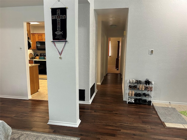 corridor with baseboards, a textured wall, and wood finished floors