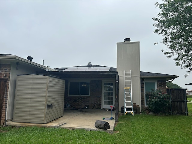 back of property featuring brick siding, a yard, a patio, and solar panels