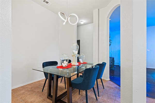 dining room featuring arched walkways, tile patterned flooring, visible vents, and baseboards