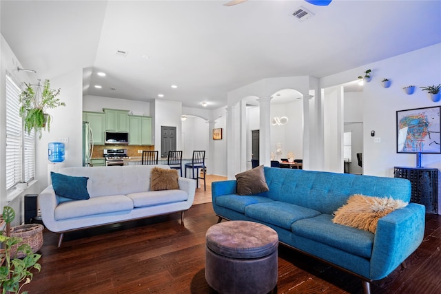 living area with ornate columns, visible vents, dark wood-style flooring, arched walkways, and recessed lighting