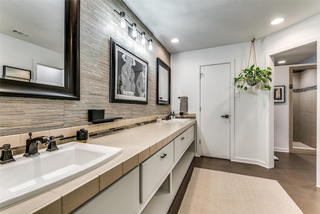 7509 Spring Meadow Ln, Garland, TX 75044 - bathroom featuring recessed lighting, tiled shower, backsplash, double vanity, and tile patterned floors