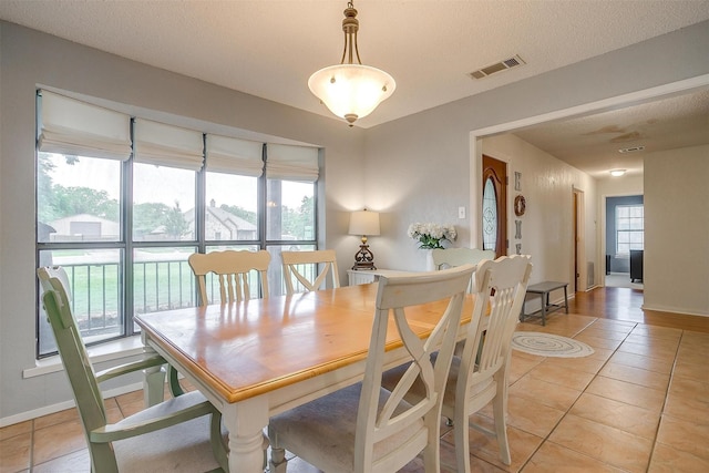 dining space featuring baseboards, visible vents, and light tile patterned floors