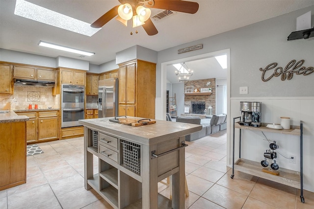 kitchen featuring light tile patterned flooring, appliances with stainless steel finishes, ceiling fan with notable chandelier, tasteful backsplash, and visible vents