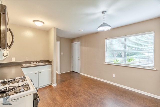 2317 Yorktown Dr, Abilene, TX 79603 - kitchen featuring wood finished floors, a sink, baseboards, white gas range oven, and white cabinets