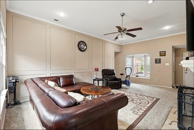 living room with ceiling fan, ornamental molding, light carpet, a decorative wall, and baseboards