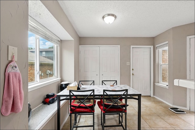 dining space featuring a textured ceiling, baseboards, and light tile patterned floors