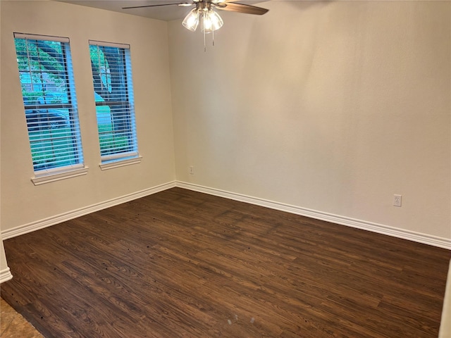 spare room with a ceiling fan, baseboards, and dark wood-type flooring