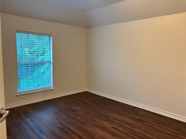 spare room featuring baseboards and dark wood-style flooring