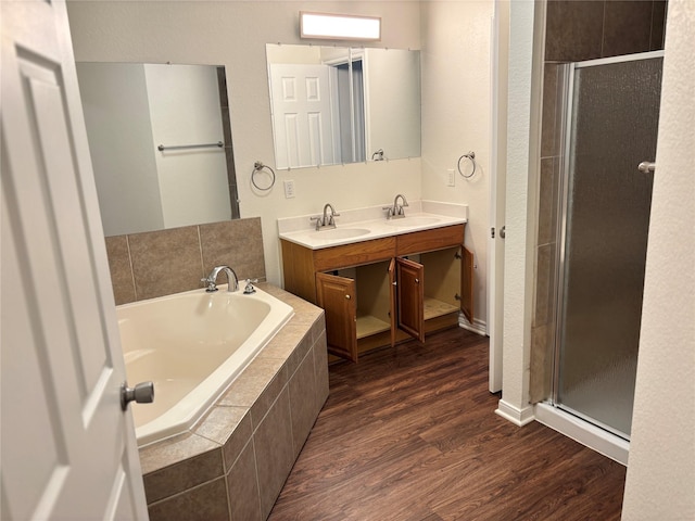 full bathroom featuring wood finished floors, a sink, a garden tub, and a stall shower