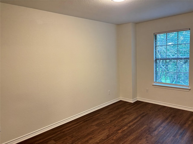 unfurnished room with dark wood-type flooring and baseboards