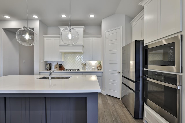 kitchen with appliances with stainless steel finishes, a sink, light countertops, white cabinetry, and dark wood-type flooring