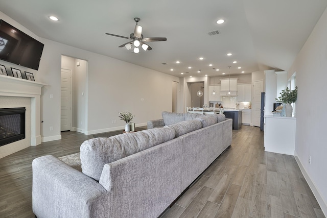 living room featuring baseboards, ceiling fan, wood finished floors, and visible vents