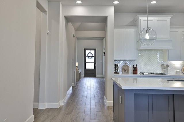 kitchen with light wood-style floors, light countertops, white cabinets, backsplash, and stainless steel gas stovetop
