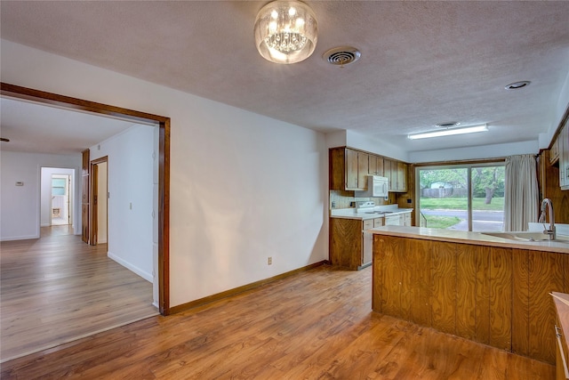 kitchen with light countertops, baseboards, white microwave, and light wood-style flooring