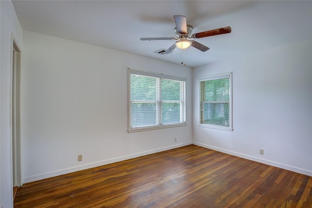 unfurnished room featuring baseboards, ceiling fan, dark wood-style flooring, and visible vents