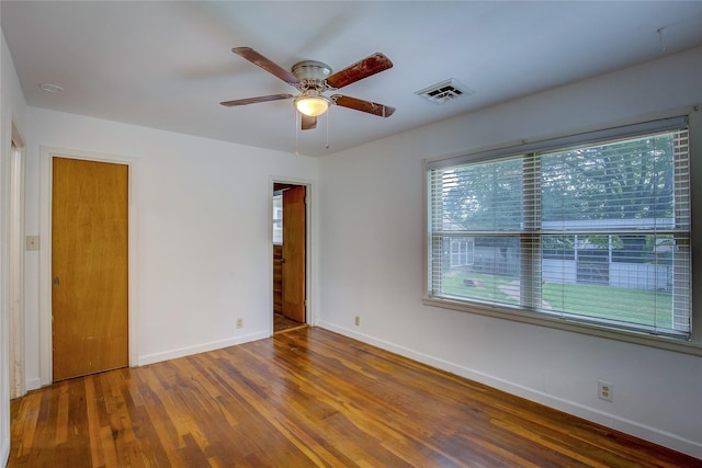 spare room with visible vents, a ceiling fan, baseboards, and wood finished floors