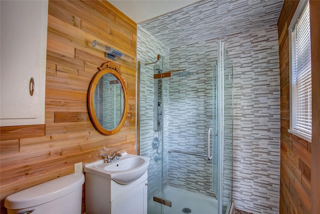 bathroom with vanity, wood walls, toilet, and a shower stall