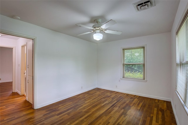 unfurnished room with baseboards, a ceiling fan, dark wood finished floors, and visible vents