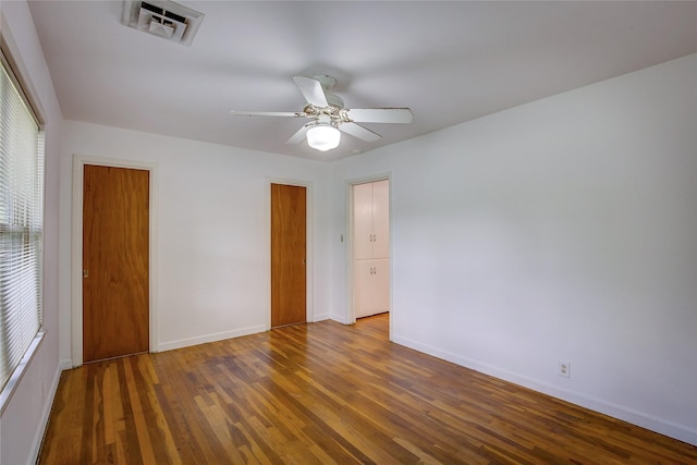 unfurnished room with baseboards, a ceiling fan, wood finished floors, and visible vents