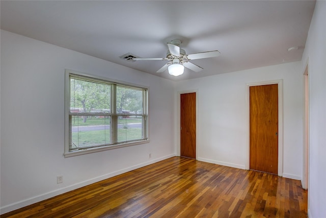 spare room featuring baseboards, ceiling fan, wood finished floors, and visible vents