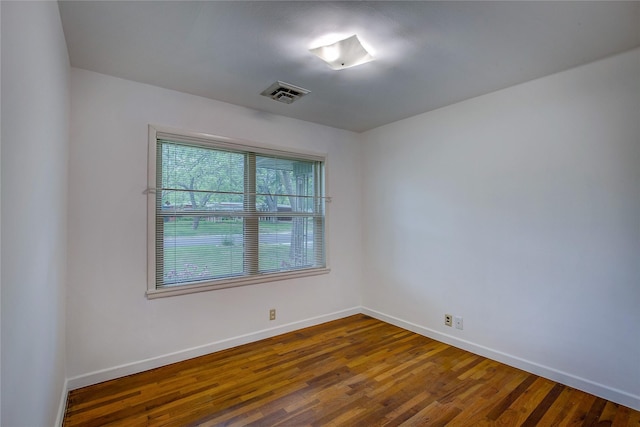 spare room with baseboards, dark wood finished floors, and visible vents