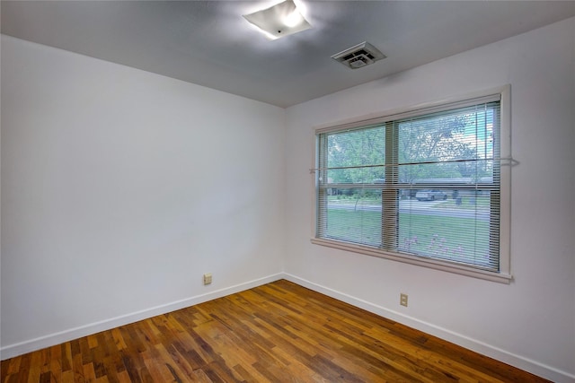 unfurnished room with visible vents, baseboards, and wood finished floors