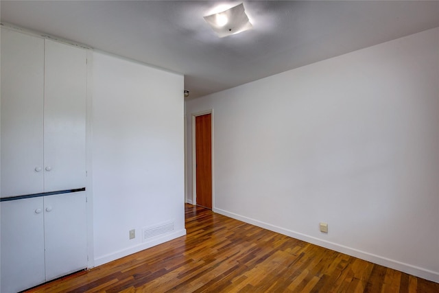 empty room with baseboards, visible vents, and wood finished floors
