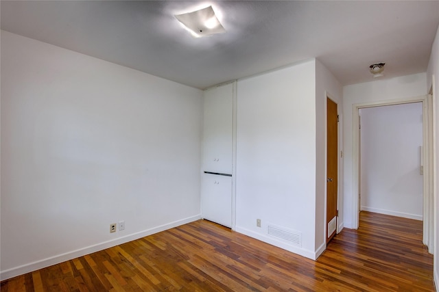 spare room with baseboards, wood finished floors, and visible vents