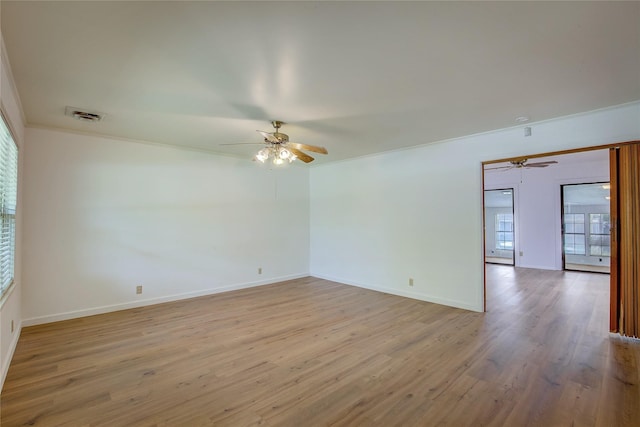 spare room featuring visible vents, a ceiling fan, light wood finished floors, and baseboards