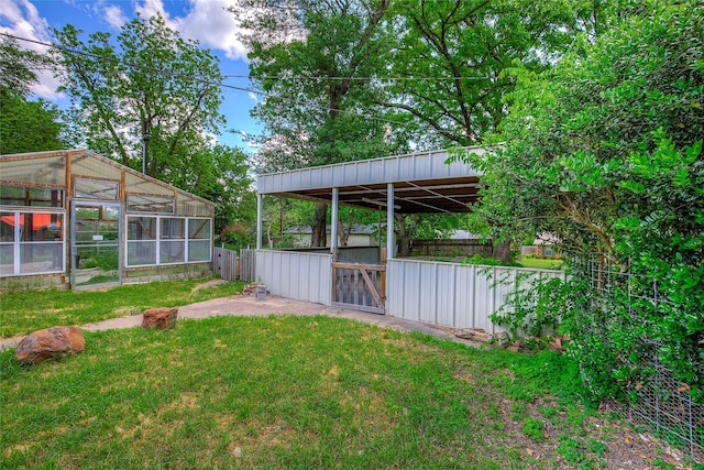 view of yard with an outdoor structure, fence, and a greenhouse