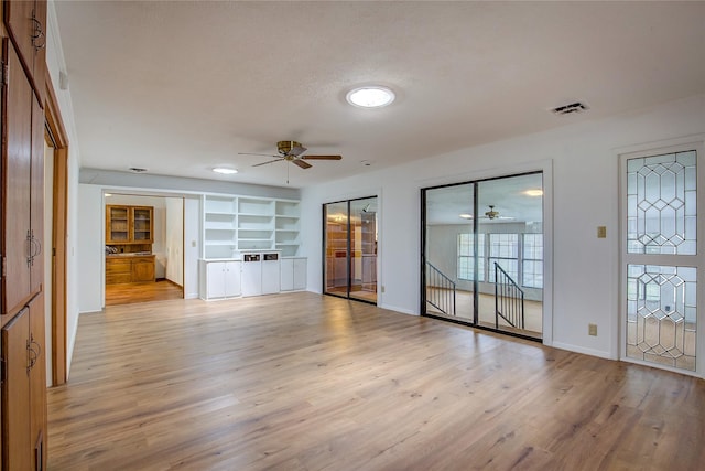 interior space featuring built in features, ceiling fan, light wood-type flooring, and visible vents