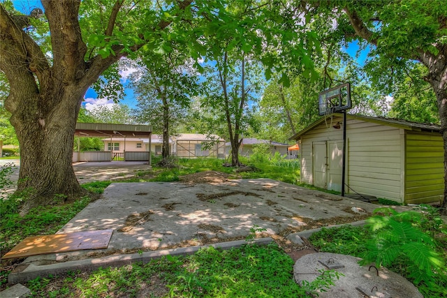 view of yard with a patio, fence, and an outbuilding