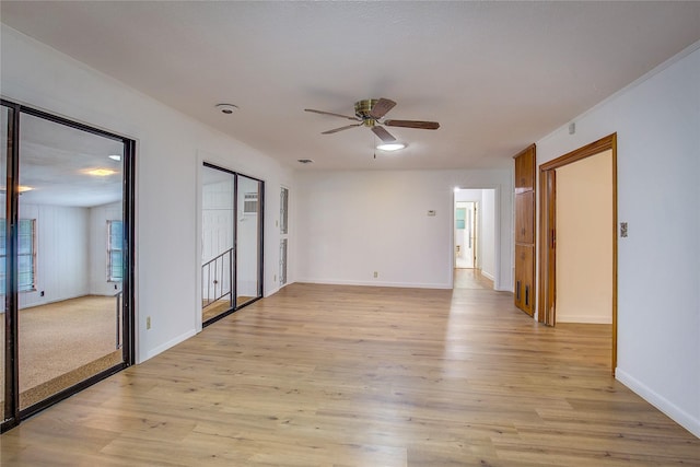 empty room featuring baseboards, ceiling fan, and light wood-style flooring