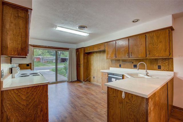 kitchen with light countertops, a peninsula, a textured ceiling, and a sink