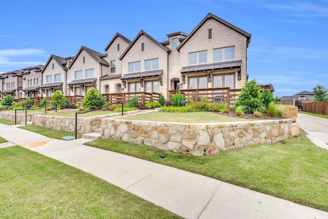 back of house with a lawn, brick siding, fence, and a residential view