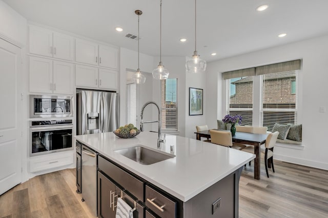 kitchen with visible vents, pendant lighting, a sink, light countertops, and stainless steel appliances