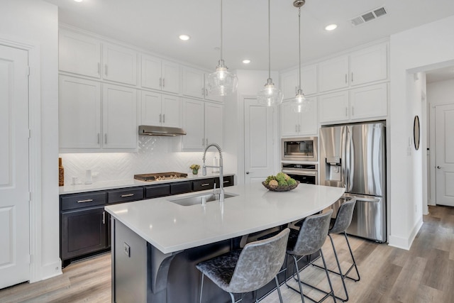 kitchen featuring visible vents, appliances with stainless steel finishes, a sink, white cabinets, and under cabinet range hood