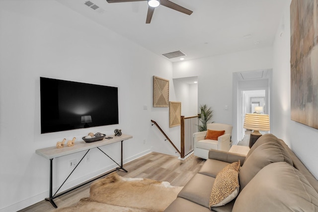 living room featuring light wood-style floors, a ceiling fan, attic access, and visible vents